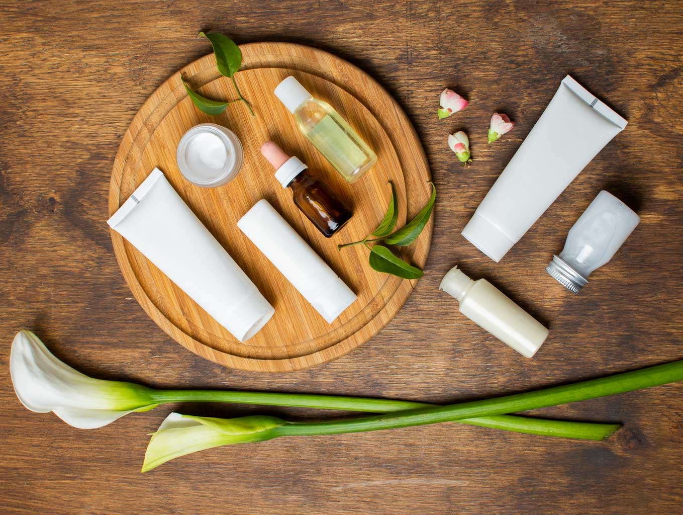 چیدمان محصولات مراقبت از پوست شامل کرم، سرم و پاککننده روی سینی چوبی